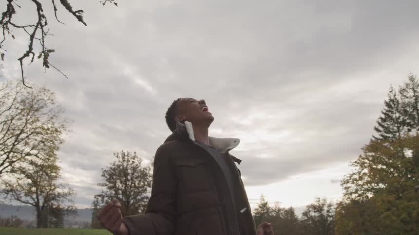 Man yelling at the sky in a grassy area with trees