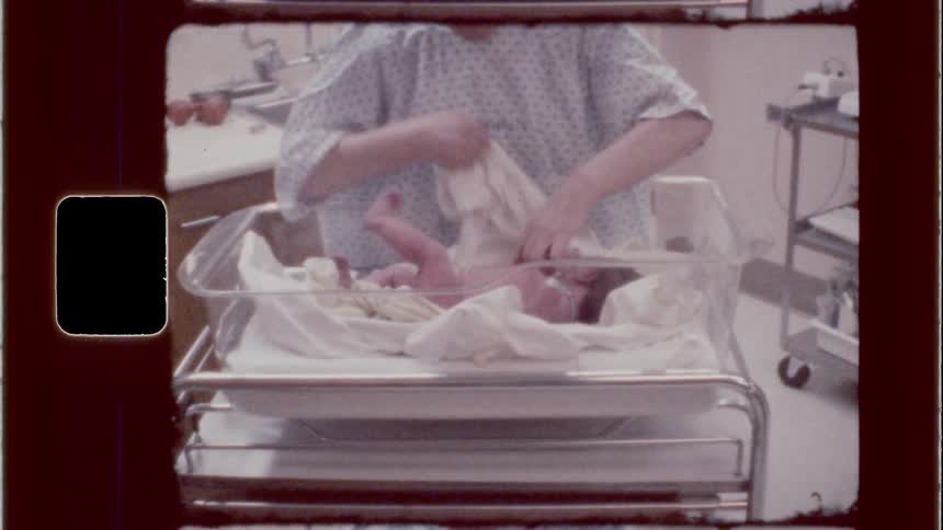Elderly nurse changes a crying baby in the hospital