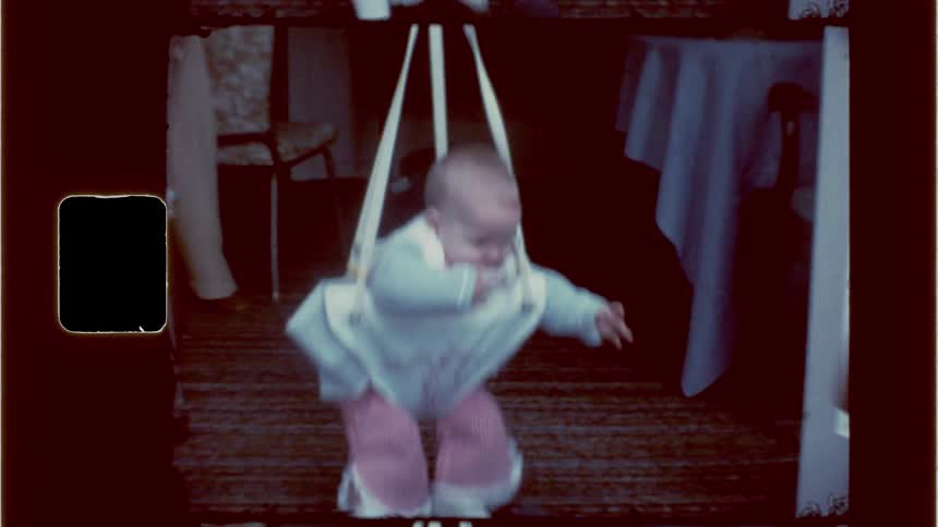 A woman gently coaxes a baby to continue bouncing in a baby jumper