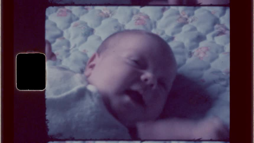 Person playing with an infant as its laying on blanket on carpet