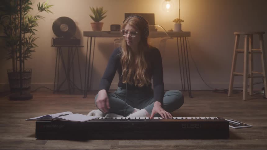 A female is sitting on the ground and playing a keyboard instrument