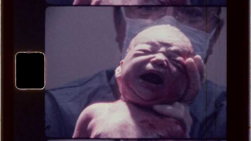 Doctor holds a newborn up so that the mother can see the child