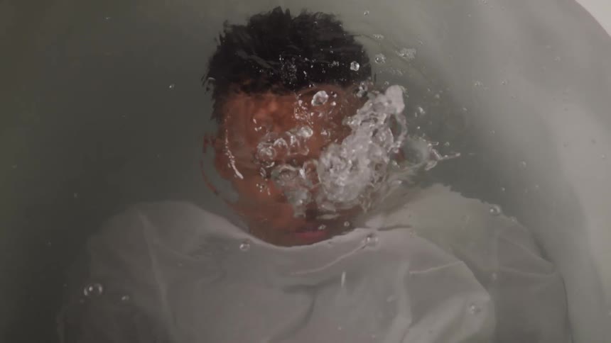 A teenager submerges himself under the tub water