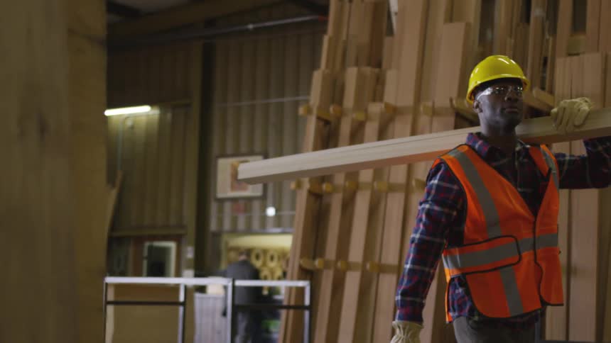 Worker at a lumber store carries a board