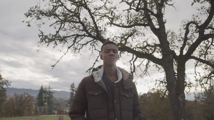 A teenager is standing by a large tree