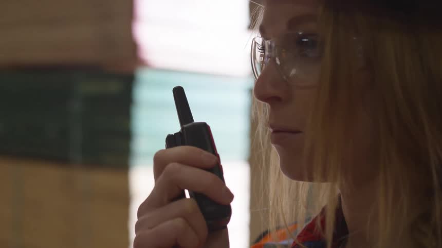 Woman speaking into a walkie talkie in a warehouse