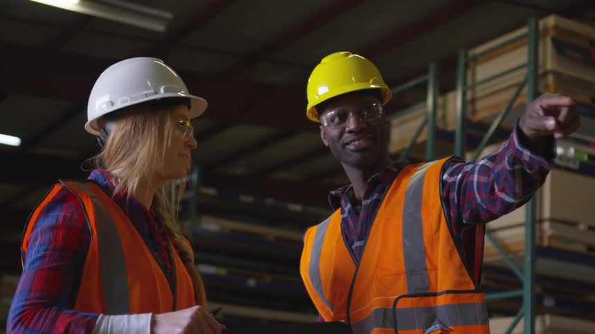 Two workers in a lumber yard are talking
