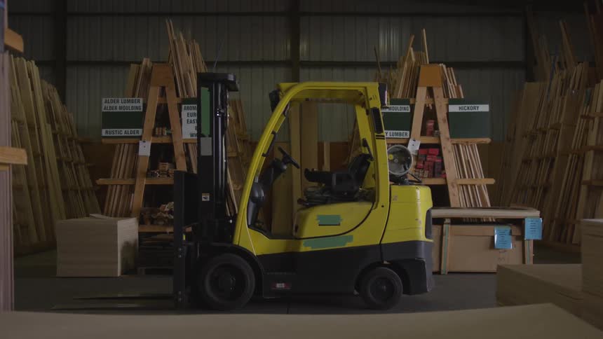 A forklift is parked by the stacks of lumber