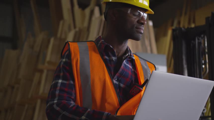 Man standing and working on a laptop computer inside a warehouse