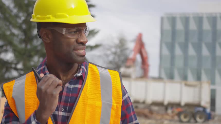 A construction worker communicates on a walkie talkie