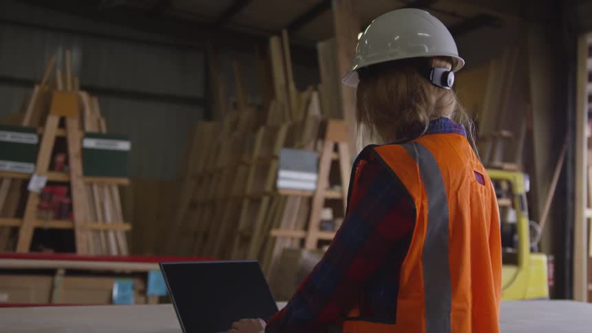 A woman construction worker is working on a laptop
