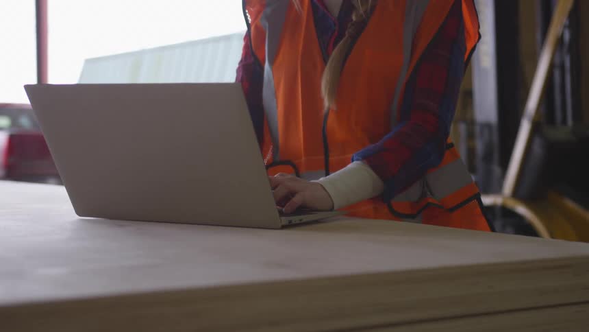 A worker is typing on their keyboard on the construction site