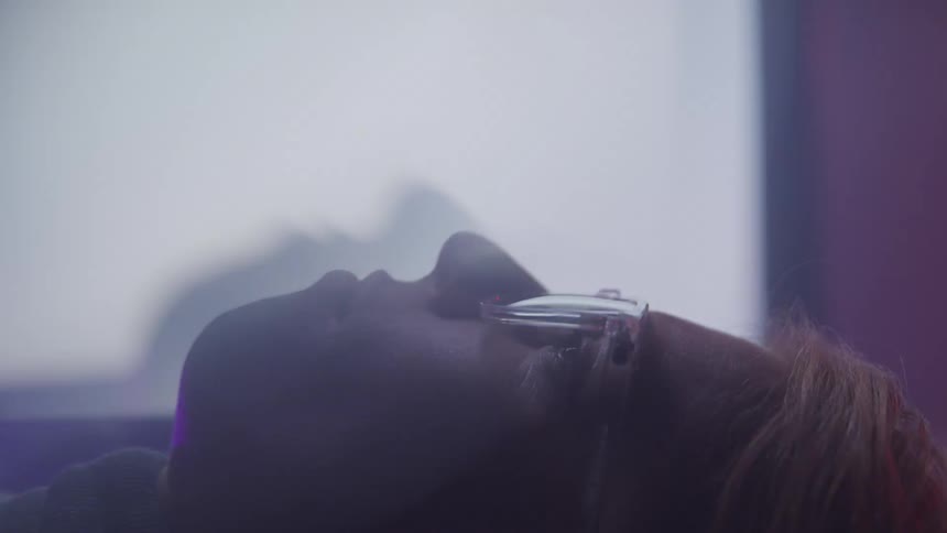 Glasseswearing woman lying down in front of a flashing television