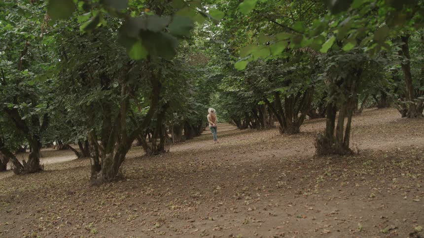 A woman is standing motionless in a forest