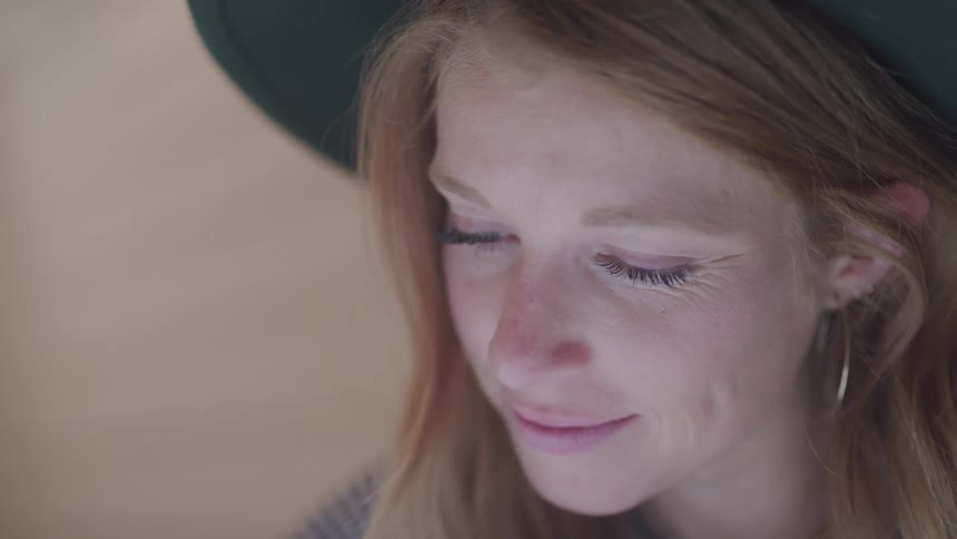 A woman is wearing a hat and is smiling