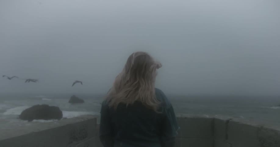 Woman stands at watches the fog covered ocean