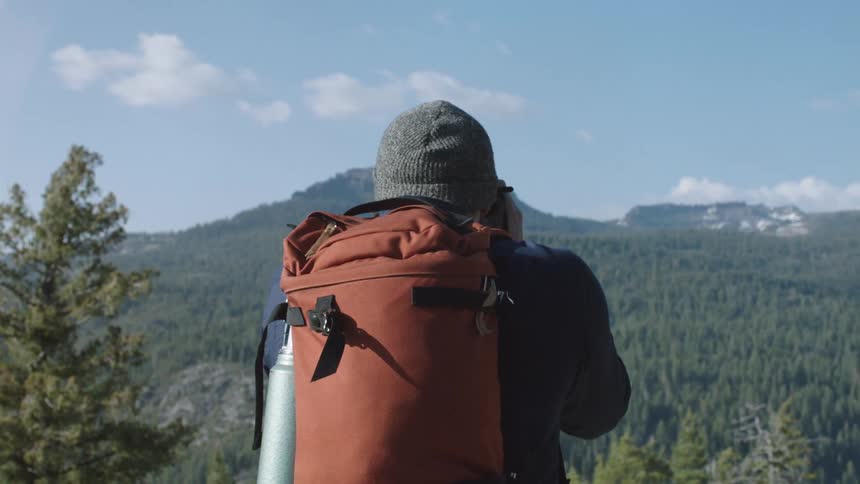 A man taking pictures on a mountain while out on a walk