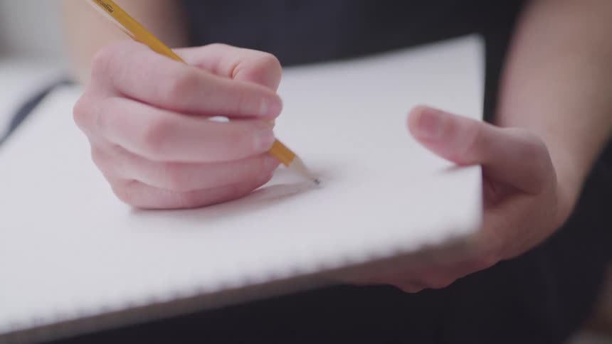 A woman writes with a pencil