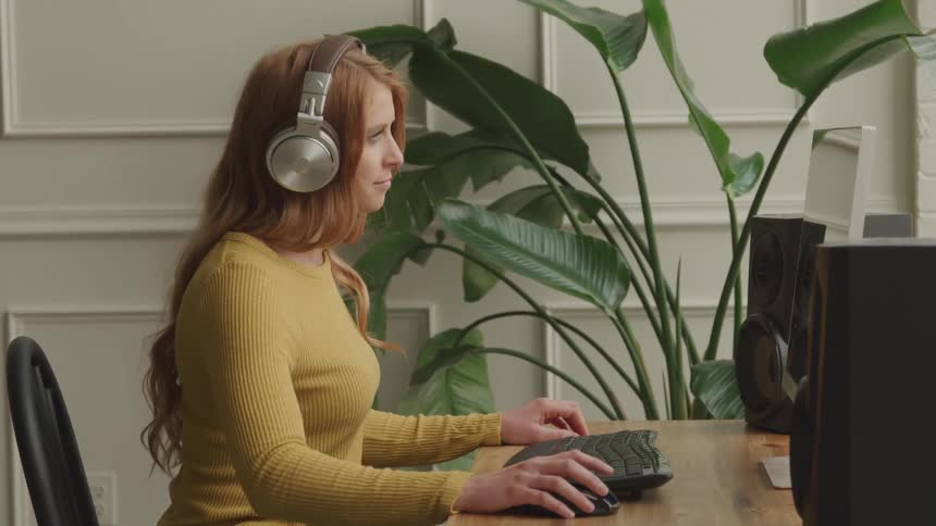 A woman is listening to music at his computer