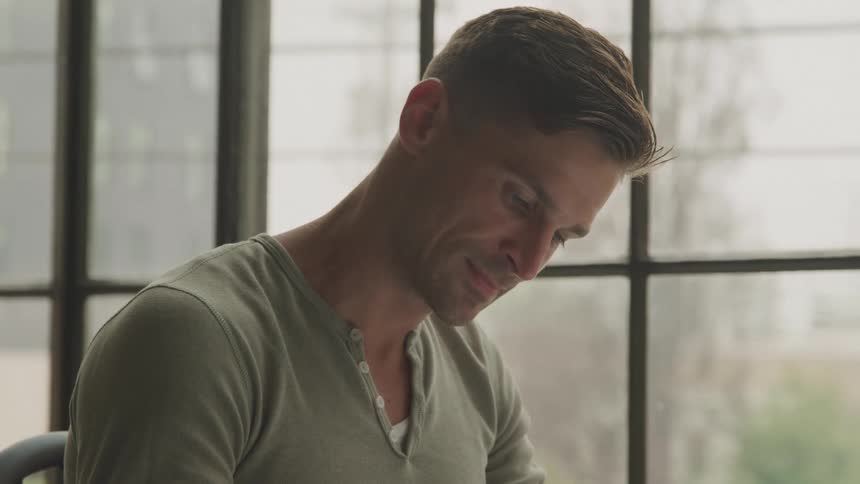 A man is looking down by the window