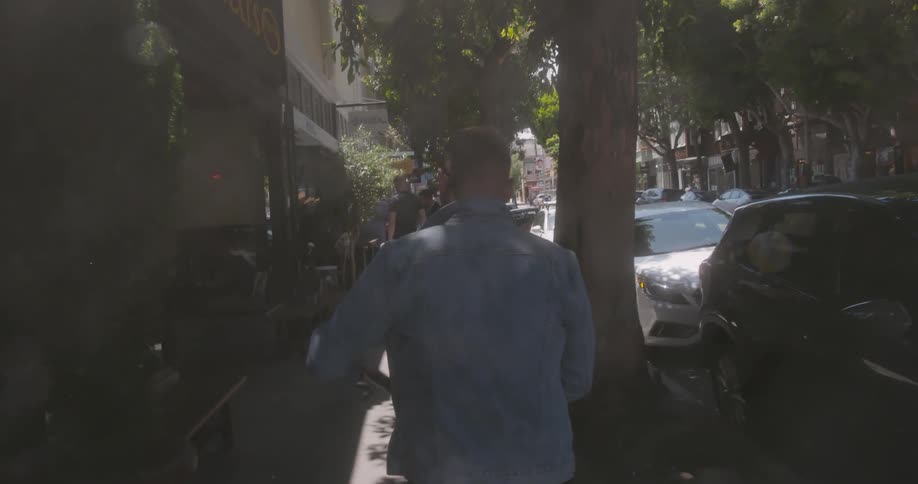 A man is walking down the sidewalk near some shops