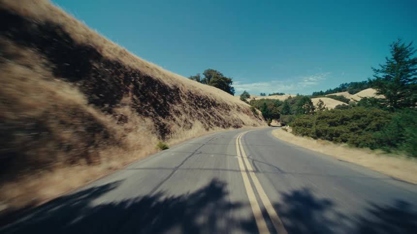 A two lane road cuts through the mountains