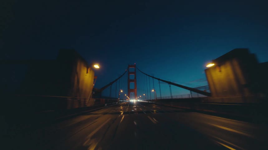 Rearview of a car driving over a highway bridge at night