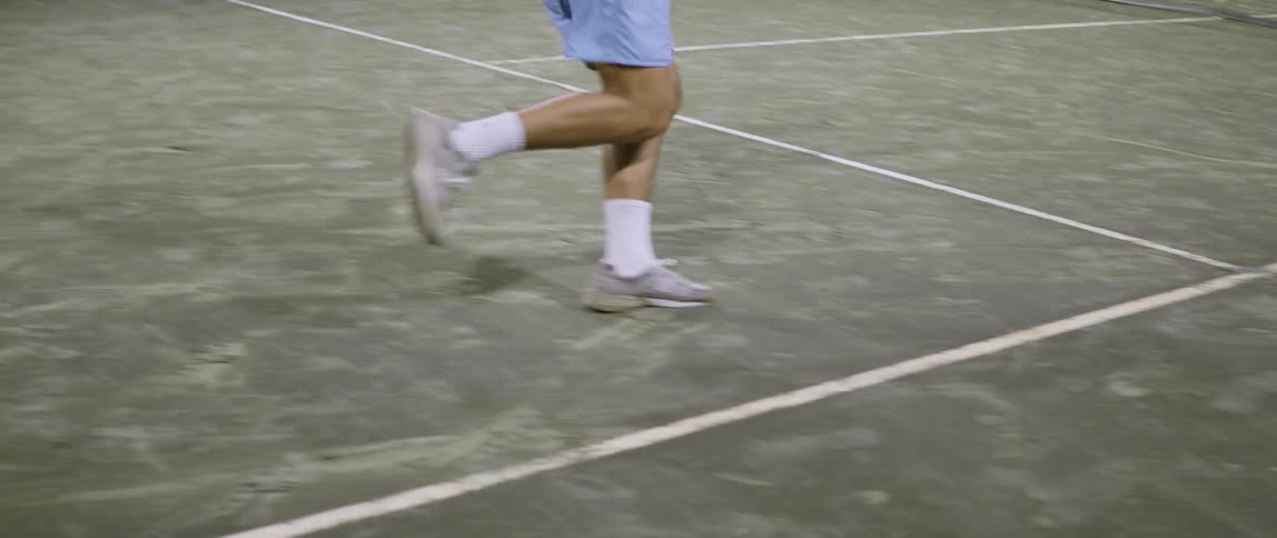 A man holding a tennis racket running around to hit the ball