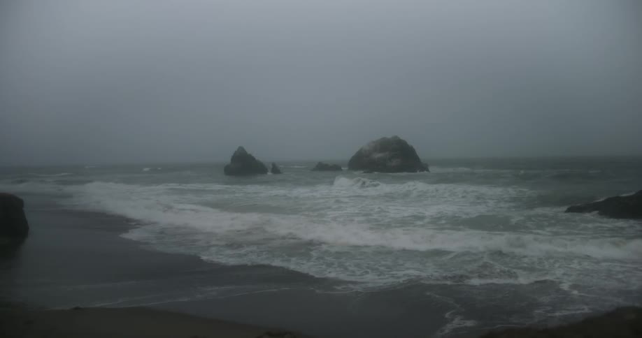 Waves crash into the shoreline on an overcast day