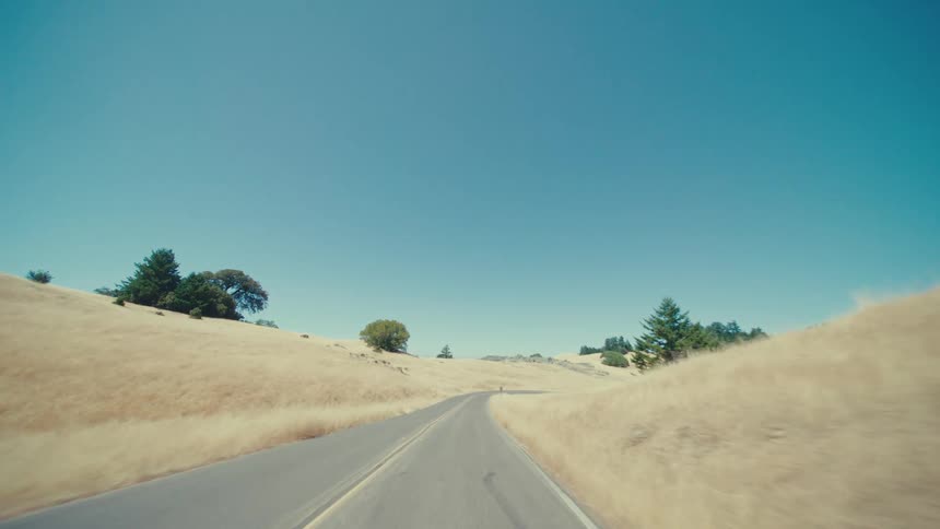 Trees and grass are on the hills by the road