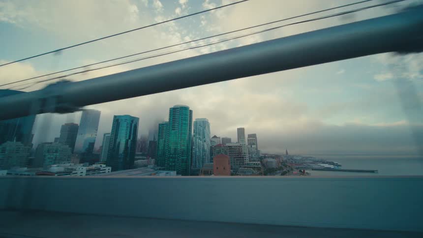 Suspension bridge leads over the water towards the area near downtown on a cloudy day