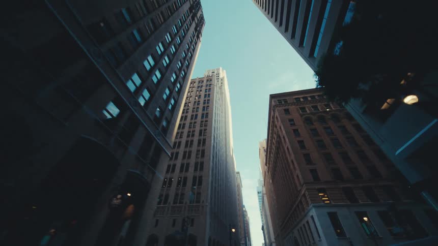 Looking up from street level tall buildings rise against a clear blue sky at morning