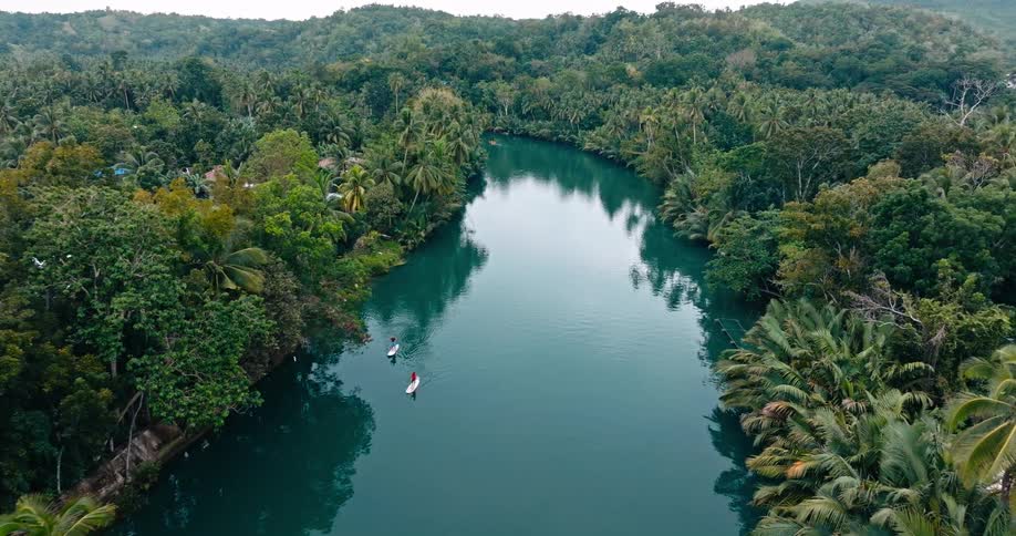 Two people paddle surf down the river