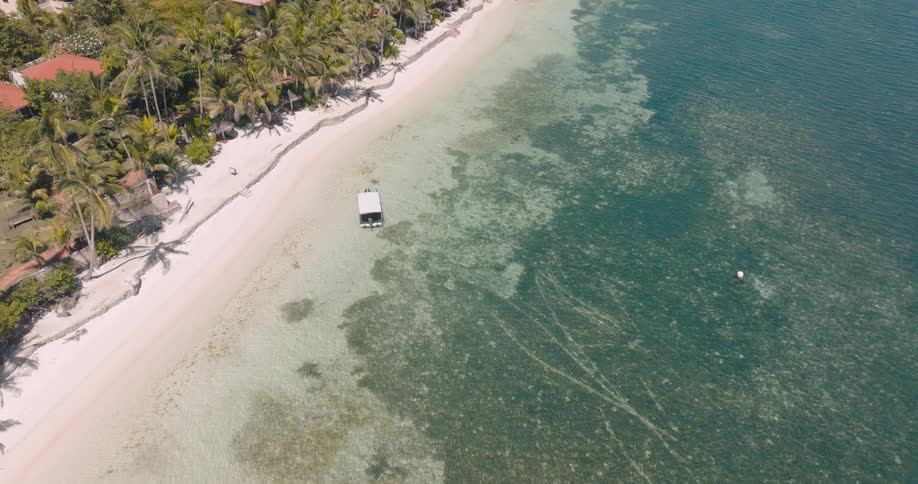 A small boat is on the sand of the tropical island
