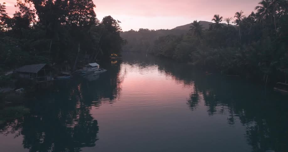 Drone view of a waterway and boats in a tropical area at sunset