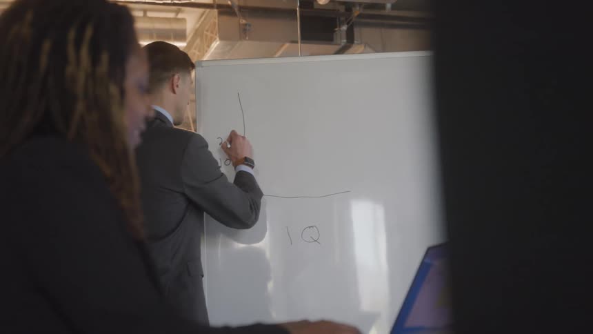 A man is writing on the whiteboard in the office