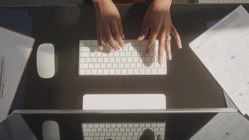 Overhead view female typing on apple keyboard at her desk