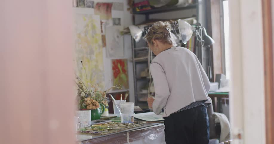 A woman is drying a painting in the studio