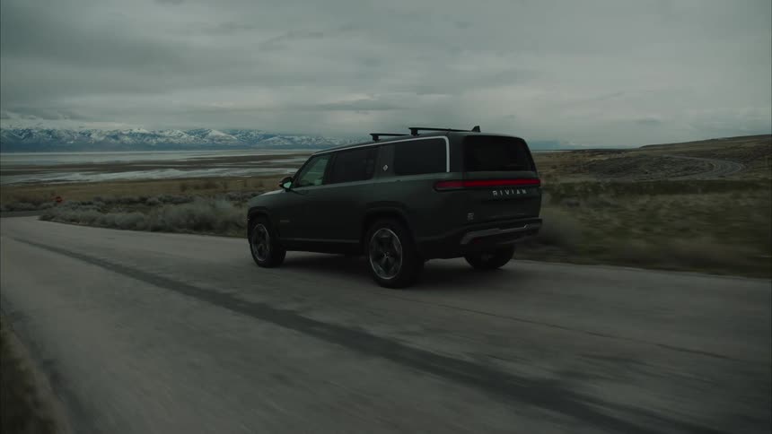 Rivian electric suv driving on a rural road in the country side