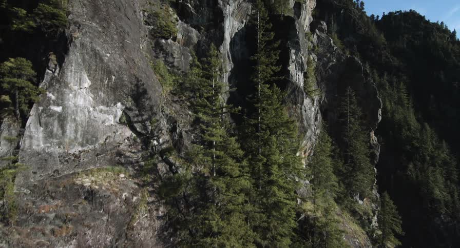 Aerial view moving along the steep side of a rocky mountain