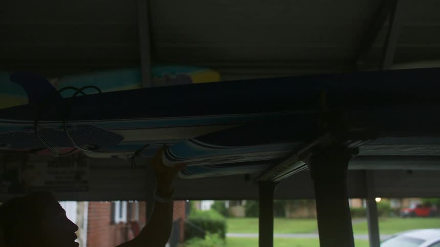 A man is loading surfboards into his garage