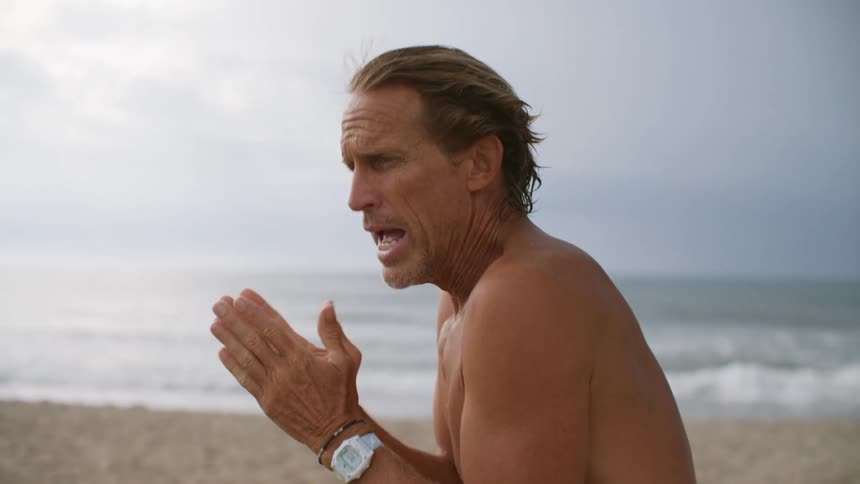 A man is teaching a surfing class on the beach