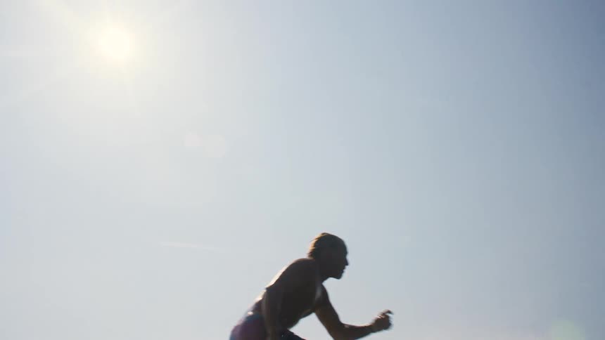 A surfer rides a breaking wave under a bright hazy sky