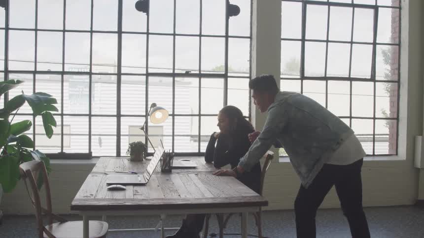An employee consulting with another about whats on her laptop
