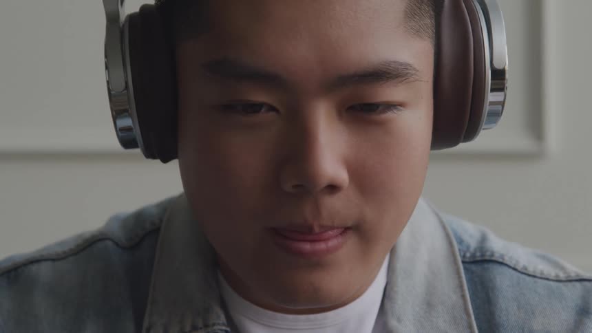 A teen is smiling and wearing headphones indoors