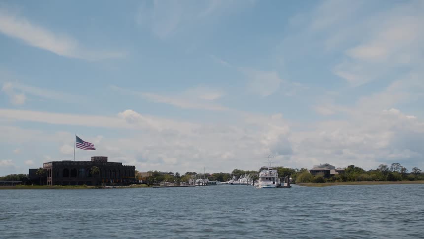A large american flag flies on the building on the shore