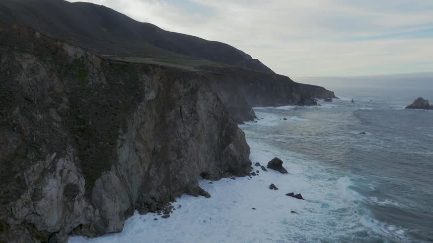 Waves crash against the cliffs below