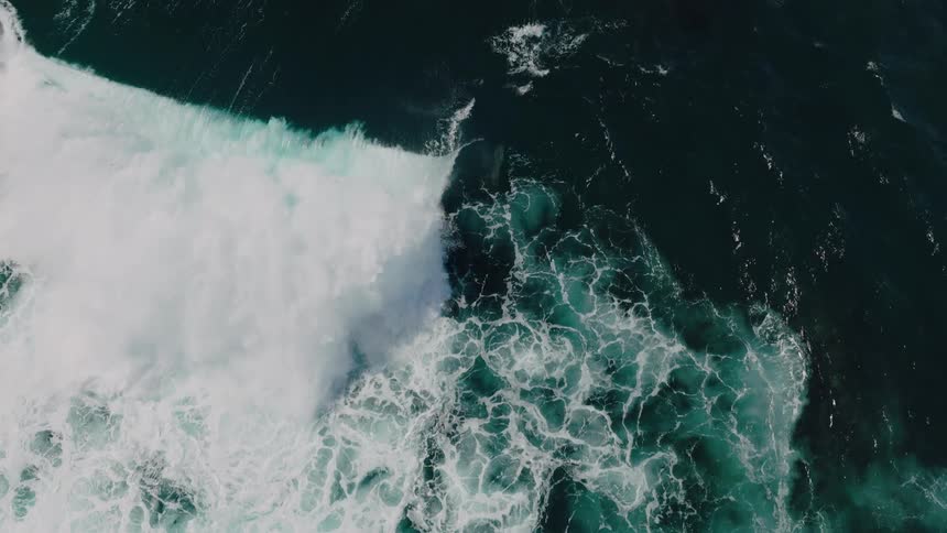 A wave rolls over in a dark ocean