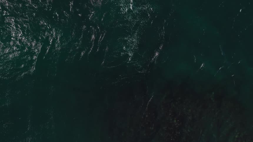 An aerial view of dark rippling ocean water with light reflecting off the waves