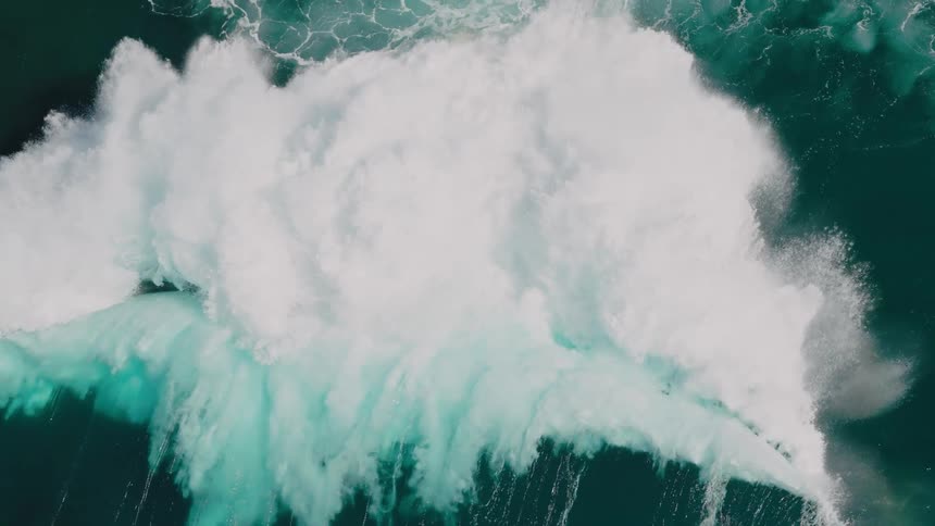 A gigantic wave crashes in the middle of a blue lagoonlooking ocean
